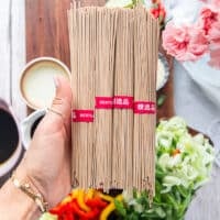 A hand holding a bunch of soba noodles showing how they look close up, raw and uncooked with the toasty color
