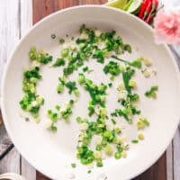 green onions cooking in a skillet with sesame oil