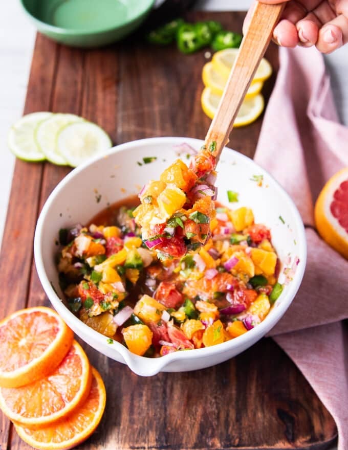 a spoon holding some citrus salsa close up showing the texture and how juicy the citrus is