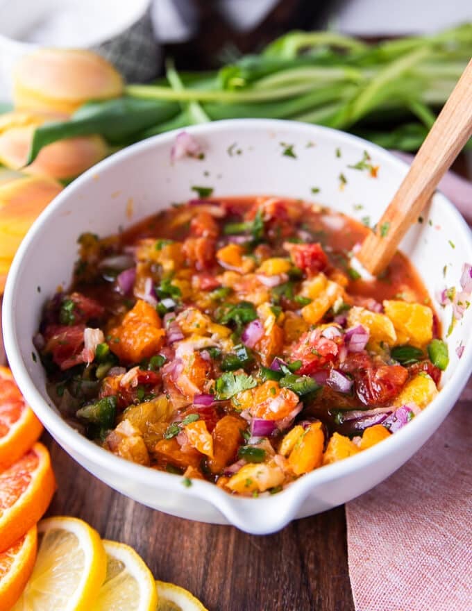 The citrus salsa mixed and a spoon is still in the bowl showing close up the textures 