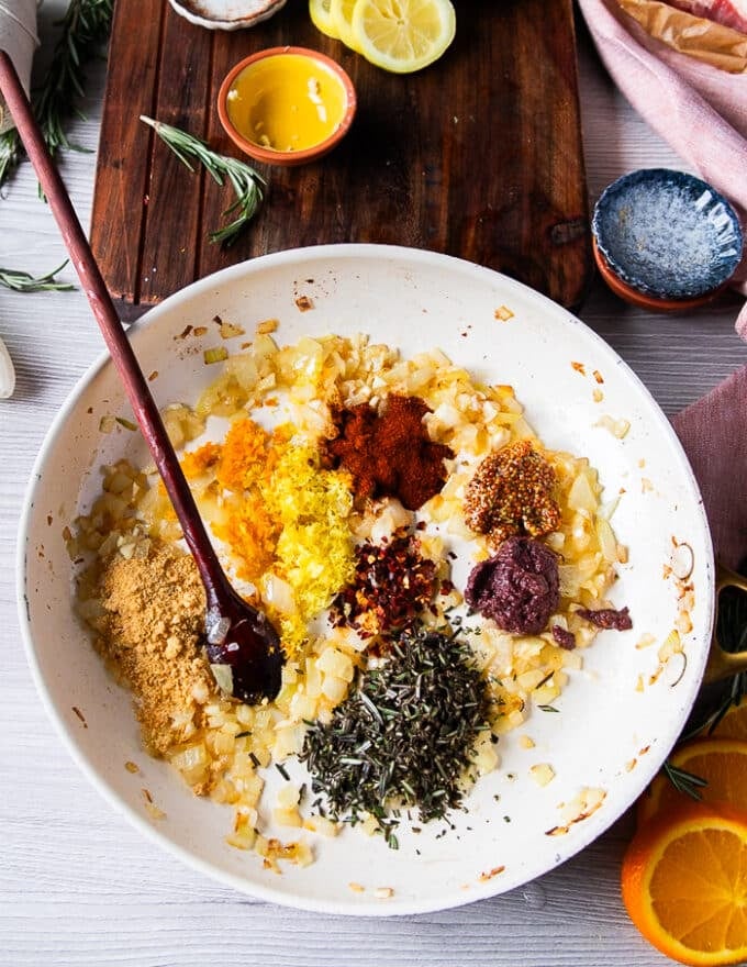 After the onions have cooked, the remaining ingredients are added including garlic, mustard, tapenade, citrus zests and spices