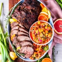 Top view of a fully roasted boneless leg of lamb, thinly sliced and arranged on a plate