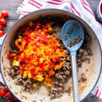 the diced tricolored peppers are added to the skillet with the cooked beef mixture