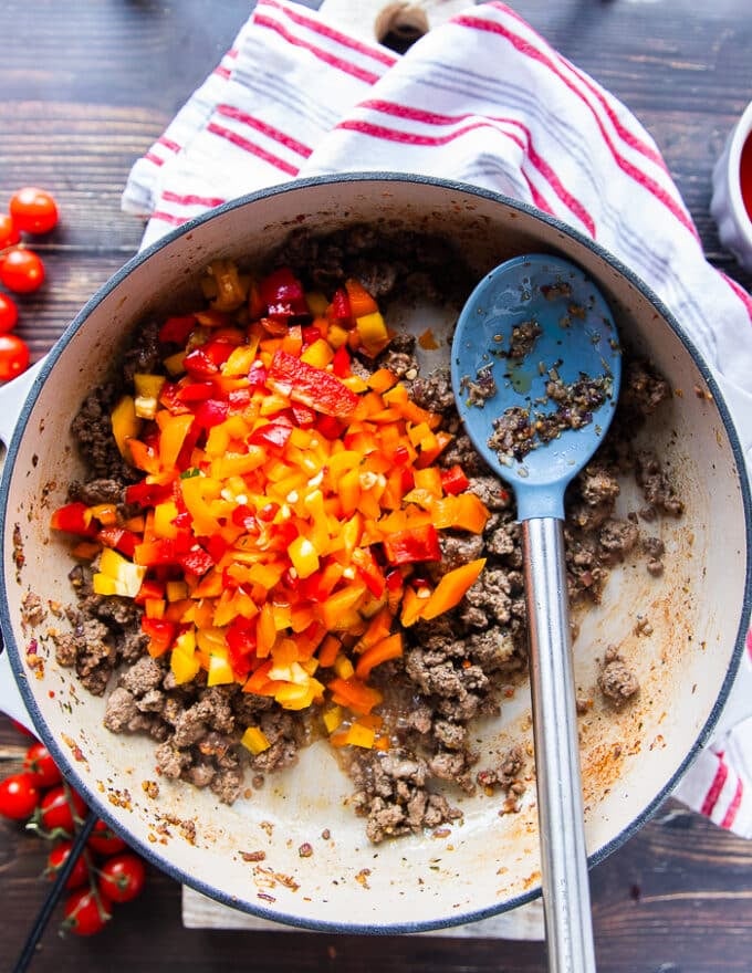 the diced tricolored peppers are added to the skillet with the cooked beef mixture 