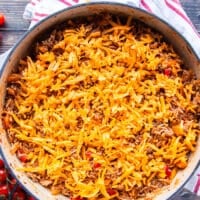 A layer of cheddar cheese is loaded over the stuffed pepper casserole and ready for the oven