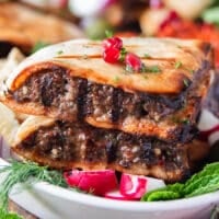 close up of one arayes meat stuffed pita showing the grill marks on the meat and bread, the juicy meat and crisp bread