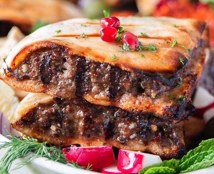 close up of one arayes meat stuffed pita showing the grill marks on the meat and bread, the juicy meat and crisp bread