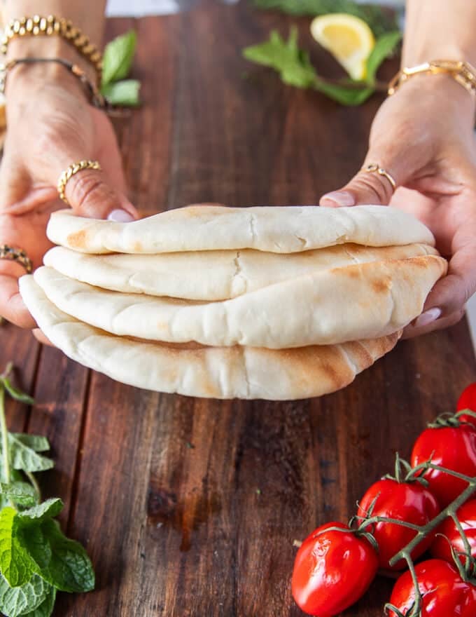 A hand holding a stack of thick pita stacks 