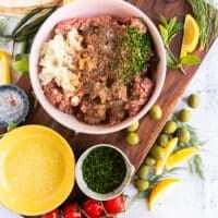 The ground meat in a bowl mixed with the spices, onions, herbs, garlic ad tomato paste