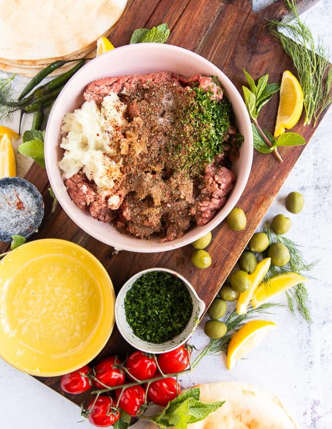 The ground meat in a bowl mixed with the spices, onions, herbs, garlic ad tomato paste