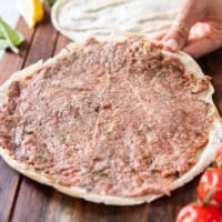 A thin layer of the meat mixture is spread over half of the pita bread