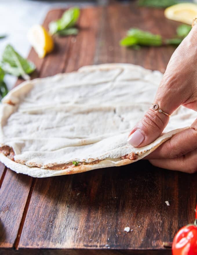 The top layer of the thin pita bread is now placed over the meat filling and pressed down 