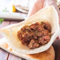 Thick pita cut in half and some meat stacked in side the half pita bread