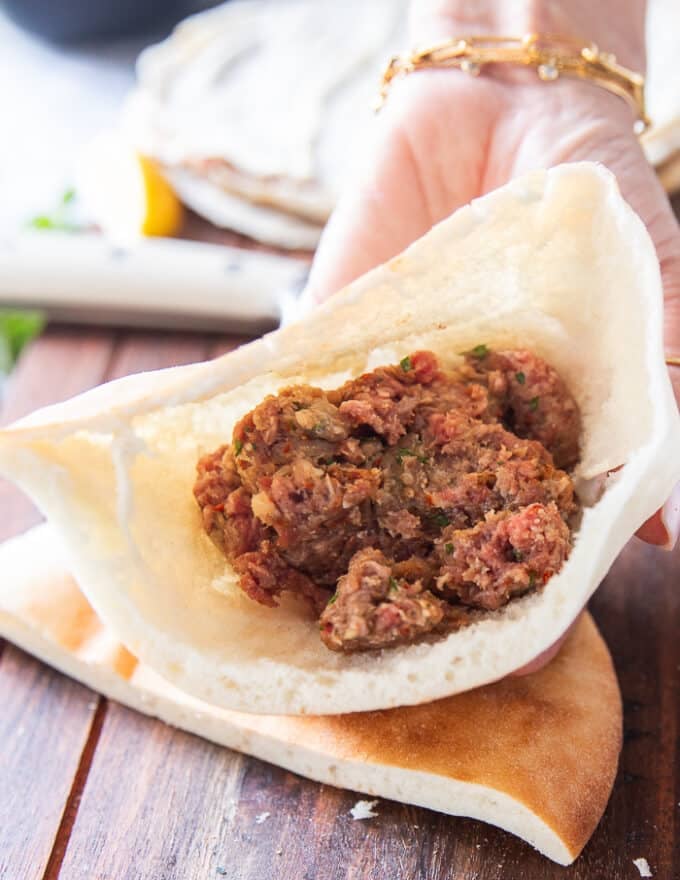 Thick pita cut in half and some meat stacked in side the half pita bread 