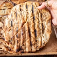 a hand holding a fully cooked arayes off the grill
