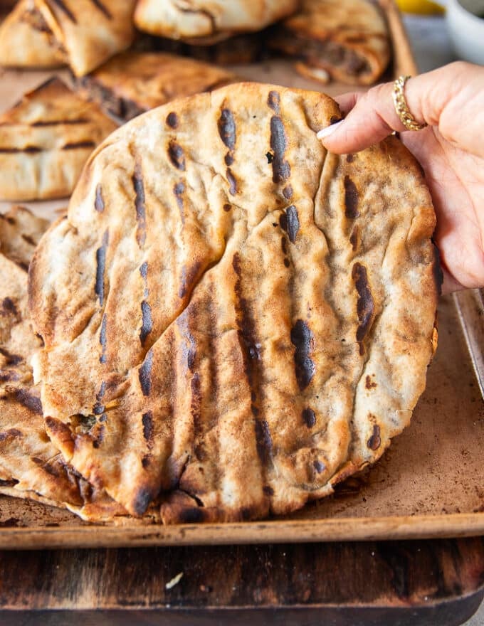 a hand holding a fully cooked arayes off the grill
