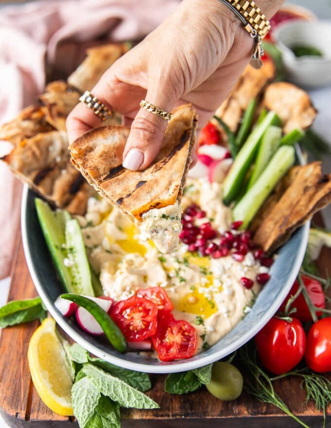 A thin pita arayes crispy and a hand holding it bitten to show the cooked meat