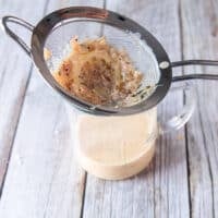 The creamy lemon sauce for black cod recipe is ready and passed through a sieve to strain in a cup