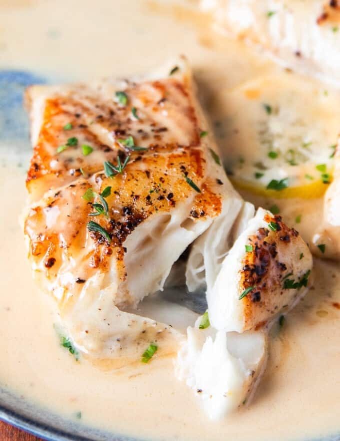 A fork breaking up the black cod showing how succulent the filet is 