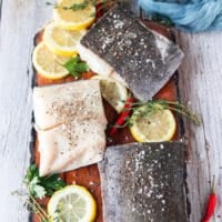 Black cod fillets seasoned on both sides with salt and pepper on a wooden board