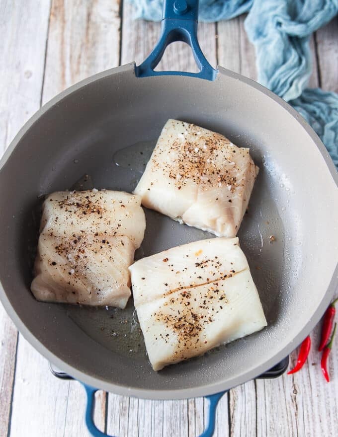 the black cod fillets are placed on a hot skillet skin side down