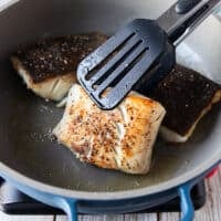 Flipped and golden black cod fish in the skillet ready to be removed