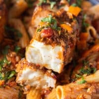 Very close up of a pieces of halibut cut in half over succulent creamy cajun pasta