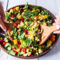 Corn and Tomato Salad in a large wooden bowl with two wooden spoons