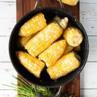 the corn is added to a pot of water and placed over the stove to begin boiling and cooking