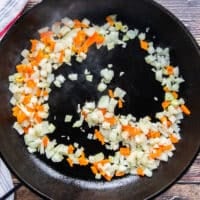 a cast iron skillet with minced onions and peppers