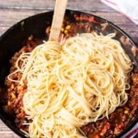 Cooked spaghetti is now added over the skillet with the taco beef and sauce