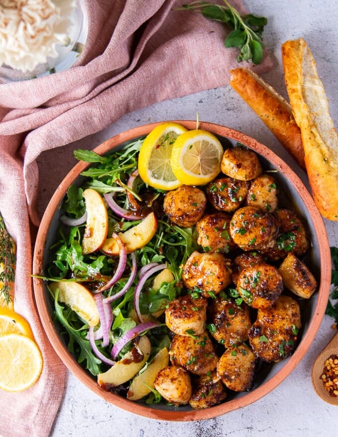 finished plate of broiled scallops with a side of salad