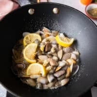 the garlic and lemon slices cooking in a skillet to make the clam pasta