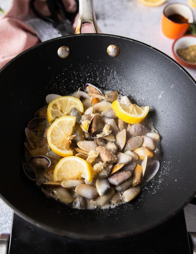 Las rodajas de ajo y limón cocinando en una sartén para hacer la pasta de almejas 