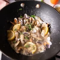 The clams are added and starting to exude some water and create a sauce in the pan