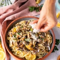 A hand adding the pasta and some parmesan sprinkle optionally
