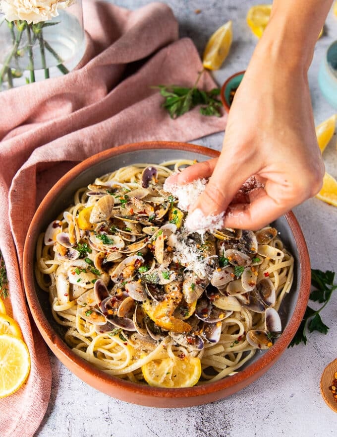 Una mano que agrega la pasta y un poco de parmesano opcionalmente 