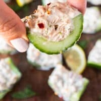 A hand holding a piece of cucumber topped with tuna salad for the best bites of tuna cucumber salad
