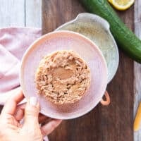 drained canned tuna in a plate and a hand holding it