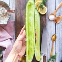 A hand holding the cucumebrs deseeded and ready to mix in the tuna salad