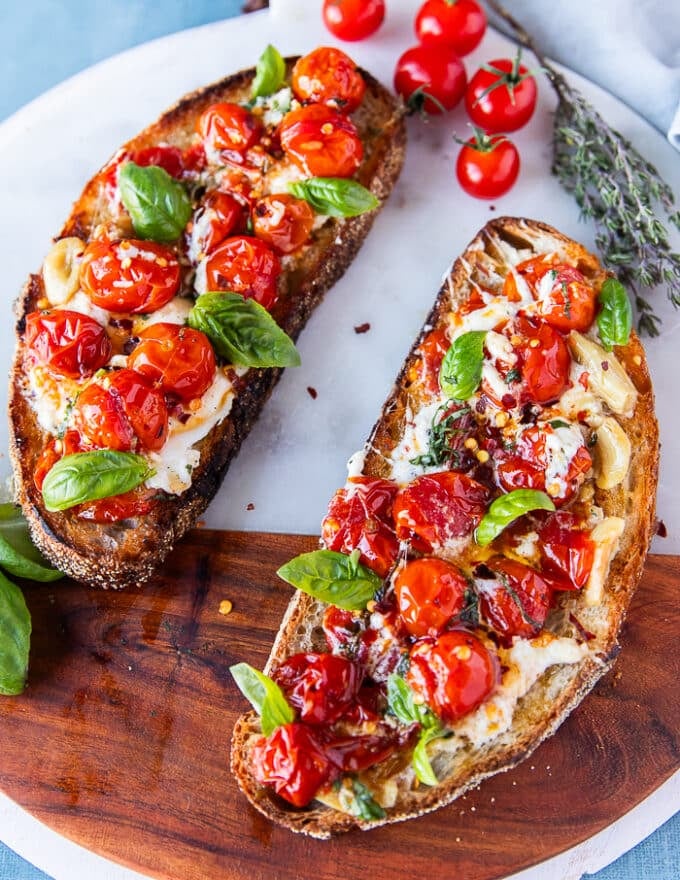 caprese toast on a marble with the tomato mixture and mozzarella and basil spread over it 