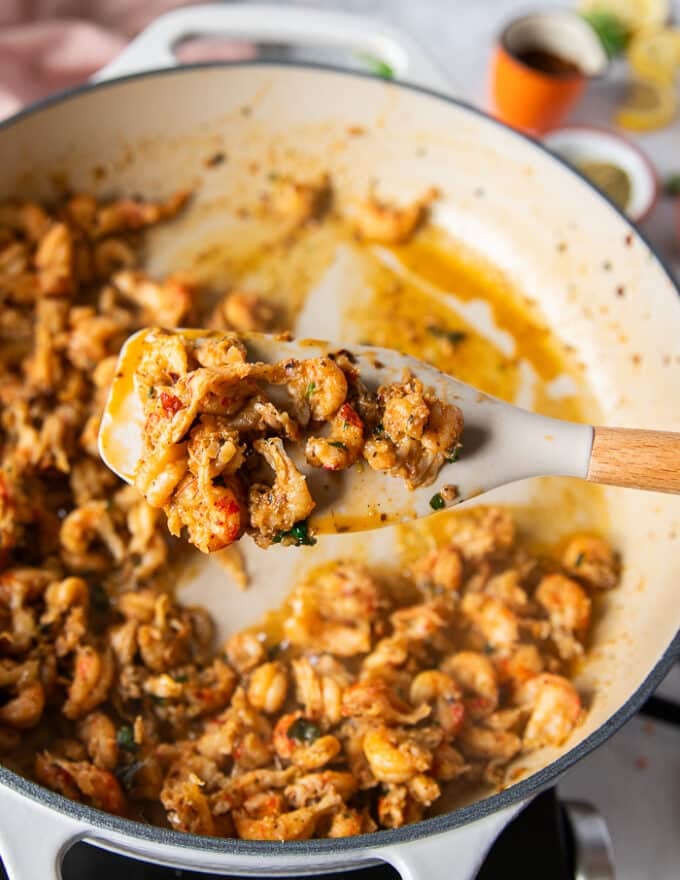 A spoon scooping a bit of the neat close up showing how well cooked the crawfish’s tail is