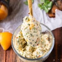 A spoon holding some butter with herbs and preserved lemons with chilli flakes and seasoning.