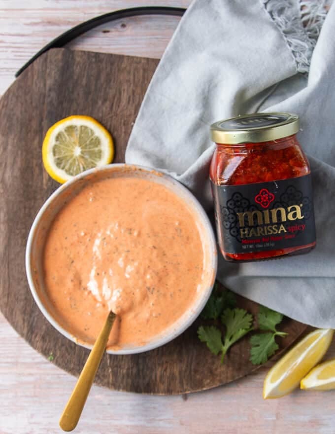 A bowl of harissa aioli with a spoon on a board ready to store