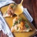 A spoon dripping some butter garlic sauce over fish