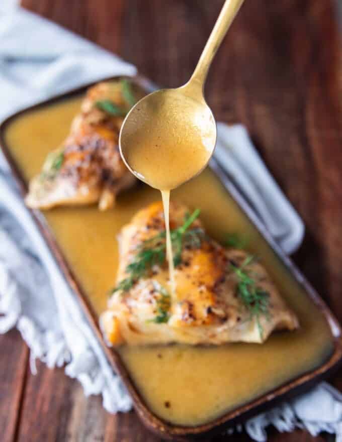A spoon dripping some butter garlic sauce over fish