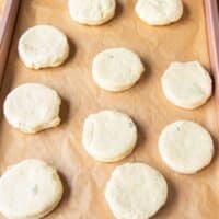 cut out biscuits arranged on a baking sheet with an inch apart space