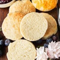 A mayonnaise biscuit split in half showing the fluffy texture on the inside on a plate with other biscuits
