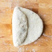 The dough on a wooden board folded in thirds