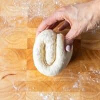 A hand holding the folded dough close up showing the three folds clearly